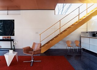 10 Smart and Surprising Under-Stair Design Solutions - Photo 5 of 10 - In this home by architect Charlie Lazor in Minneapolis, the space under this open-riser metal stair has been allocated as overflow storage and seating for the living room. Although it may initially seem like an unusable area, the height of the stair means that the space is in fact usable by someone seated or reaching for items in the storage cabinet along the back wall. By carefully placing the chairs, the space appears useful but not cluttered.