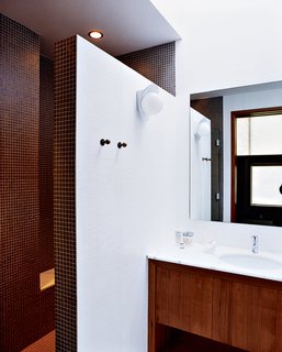 The Pace of Portland - Photo 5 of 6 - A double-size shower, clad floor-to-ceiling in tiny earth-toned tiles, was built after relocating the water heater and claiming its space. A chic yet discreet toilet is wall-hung and the tank concealed, greatly ameliorating the somewhat claustrophobic feel of the original bathroom.