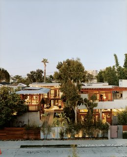 The exuberant results of Hertz’s design are visible from the street. Giant birds <br><br>of paradise, king palms, and bamboo tower above the fence. The Balinese long building, seen on the far left, is almost nautical; on the right, the original house’s rammed-earth entry wall frames its concrete layers.