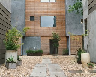 Houston, We've Solved a Problem - Photo 3 of 8 - Weathered wood tempers the gray stucco siding and provides a pleasant refuge in the community garden space. 