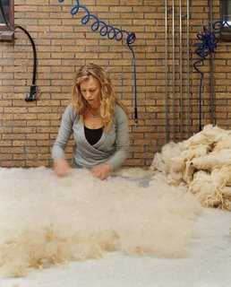 A felt maker lays Drenthe wool and raw silk onto a large table lined with bubble wrap.
