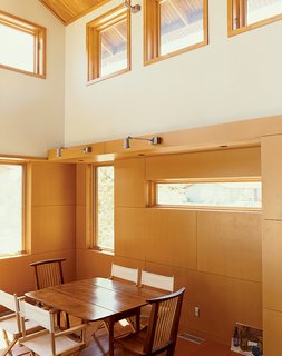 With smooth, clear-finish MDF tile-like panels that accentuate carefully located joints, this living/dining area feels bright and modern, especially thanks to the double-height ceilings and multiple windows that let in natural light. Light pours into the Ankneys’ living/dining area with its clear pine plywood ceiling, clear-finish MDF paneling on the walls, and reclaimed-fir flooring.