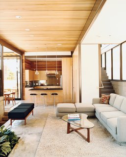 A view of the lower living space on the ground floor. Green materials used include the FSC-certified cedar on the ceiling, Permlight LED downlights, and a floor of polished concrete with fly ash mix with radiant heating underneath. The couch was designed by Glenn’s interior designer, Heidi Toll Design.