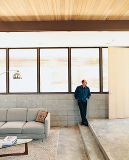 Glenn looks toward the front entrance from the northeast wall of his house. The wall is exposed concrete block with translucent Polygal windows.