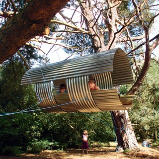 The High Life - Photo 2 of 4 - Those looking for a more down-to-earth option might consider wallowing in a pigsty, which is essentially what designer Amir Sanei constructed for his two sons. "The design decisions could be explained simply to them by referring to the needs of flying pigs," Sanei comments with a twinkle in his eye. Sanei, who is the cofounder of London-based Sanei Hopkins Architects, based most of his design on the "pig ark," the simple metal domes used to house pigs on farms surrounding his house in Suffolk. But since flying pigs have some special needs, some alterations to the design had to be made. <br><br>Sanei elevated the Flying Pigsty six feet off the ground with four ropes slung between two trees "because flying pigs cannot fly far from the ground, and they need good clearance when they come into land." Entrance to the ten-foot-long, galvanized steel–and–scrap wood Flying Pigsty is via a ladder or rope at back. The entire project was completed over a long weekend in August 2005 for around $850. <br><br>Though most times Sanei allows his sons to play freely in the Flying Pigsty, he has strictly forbidden them to enter during moments of twilight when the pigs return to feed. "The boys have permission to use the structure," Sanei says sternly, "only when the flying pigs aren’t there." br><br><br>br><br><br>Photo by Amir Sanei.