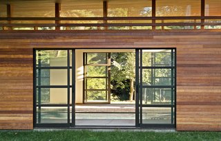 Sliding glass doors open to reveal the interior of the pool house, which boasts a line of clerestory windows just below the roof.