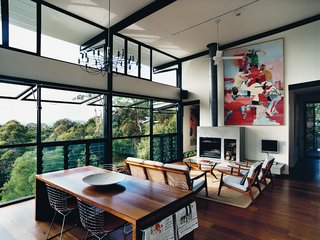 The open-plan living room was inspired by the couple’s previous residence, a London loft. The paintings are by Dunlop. The louvered floor-to-ceiling windows, ceiling fan, and sliding deck doors usher in sea breezes and encourage good air circulation.