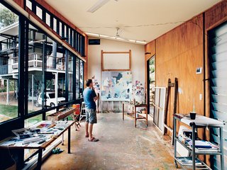 In his detached painting studio, Dunlop considers a work in progress. The building is oriented east-west to avoid direct sunlight, and the long, narrow shape enables the artist to get some distance from his paintings as he works. An oversize front door and angled ceiling accommodate extra-large canvases; the plywood walls and floor can <br><br>ably endure a beating, or, as is more likely, stray splashes of paint.