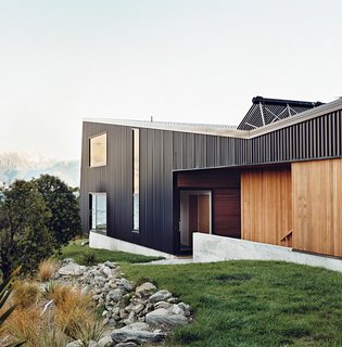 Nature Nurtured - Photo 7 of 11 - The home is mostly clad in black trapezoidal-profile steel, with cedar boards lining what the owners call the "human spaces"—external passages between buildings. A solar hot water system perches on the roof.