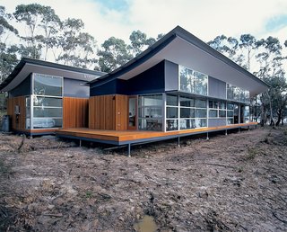 With its bold, upswept profile, the roof gives this otherwise simple house its distinctive character. But those curves are not merely for show. The concave forms are integral to the dwelling’s self-sufficiency because they act as water collectors and sun protection. When rain hits the roof, it runs down into holes punched into the valleys created by the tilt of the corrugated-steel sheets. Underneath these holes, which are too small for leaves to penetrate, the water collects in a concealed gutter and is piped down the side of the house and underground to the nearby water tanks. Using a combination of computer technology and onsite observation, the architects calculated how far the main roof would have to overhang the north elevation to let in as much low winter sun as possible, while shielding the interior from the more extreme summer sun. The nearly 13-foot-high expanse of glazing that embraces the views really needed protecting—and the four-foot eave created by the sweep of the main roof does the job well.