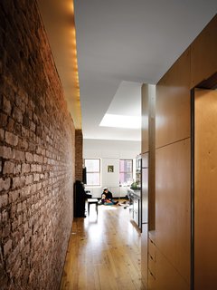 Storage-Smart Renovation in New York City - Photo 9 of 14 - Although the apartment’s only windows are on the far ends of the space, skylights keep things bright. Recessed lighting along the brick wall supplements the daylight.