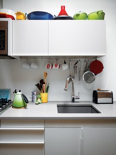 Storage-Smart Renovation in New York City - Photo 11 of 14 - In the kitchen, colorful cookware accents white surfaces.