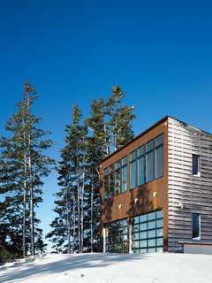 The roll-up garage doors on the ocean-facing facade open onto a large deck. From the living room the deck appears to extend right out to the sea like a floating dock.