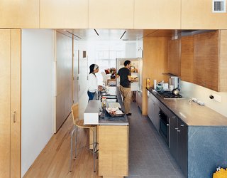 Harlem Renaissance - Photo 8 of 11 - In the kitchen, the architects contrasted the oak floor, bamboo cabinetry, and birch walls and ceiling with what architect Jonathan Knowles calls "a family of grays": granite floor tiles, limestone countertops, and the steel stairway. The birch wall behind Yvette is actually the sliding door to the pantry closet.
