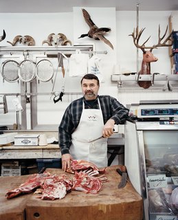 A butcher poses at the meat counter inside the Italian Market.
