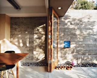 The elevated dining room opens out to a side patio, which climbs the wall just behind the house.