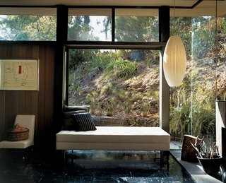 Near floor-to-ceiling window walls frame views of the landscaped hillside.