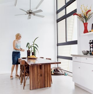 Custom furniture softens the house’s aesthetics, including a dining table by AXIS Millwork and Fabrications. Ceiling fan by Craftmade.
