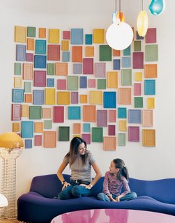 Clémence and daughter Clara, nine, relax on a purple Pierre Paulin 261 sofa below an installation by artist Alan McCollum. A small family of Verner Panton 1969 Wire lamps, featured in the inaugural Kreo exhibition, live to the left.