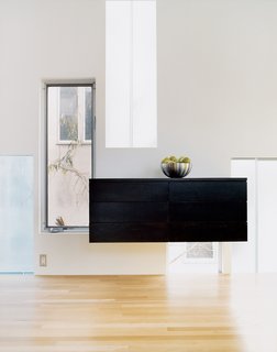 A custom-fabricated sideboard of birch, in a coffee-colored stain, finds its niche among the gathering of windows.