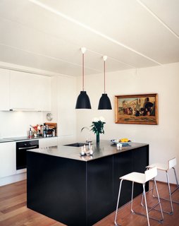 White walls, oak floors, and wooden window panes exude a calm, Danish-modern vibe. A stainless steel kitchen island, designed by BIG, is lit by Cecilie Manz’s Caravaggio lights.