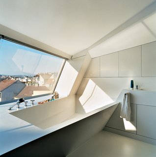 The Penthouse Has Landed - Photo 5 of 16 - The cavity for the bathtub is part of the same continuous form-world as House Ray 1’s sloping roofscape. The white tub is made from Corian; the faucet is by Dornbracht.