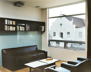 Making Sense of the City - Photo 3 of 11 - All the west-facing windows frame the church across the street. Bookcases, also designed by MS-31, line the back wall. When the chairs and couch from Restoration Hardware face each other, it’s a cozy little living room. Turn the chairs around and it’s a full theater complete with an 11-by-17-foot image projected on the wall.