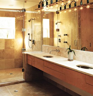 The master bath is a simple rectangle. "Like the kitchen, I designed it so that no stuff was laying around," Erik said. The surfaces are natural and subdued; a simple palette of tones, colors, and materials unifies the space. Travertine marble was used on the floors, shower, and countertop. The closet and cabinetry are maple. Erik designed the light fixture himself because, he says, "there was nothing I could find that fit the scale of the room." He used cold-rolled steel with exposed wires to give it an industrial feel.