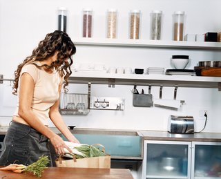 Mandi Rafaty’s girlfriend, Yoly Guerra, unpacks groceries in preparation for dinner. The kitchen cabinets are off-the-shelf models from IKEA, and all knives are stored on a space-saving magnetic hanging holder on the wall. Two floating, open shelves above the Tag Front cast-concrete sink and Frigidaire dishwasher act as home base for plates and dishes, while a convection oven by Sharp, Turbo Air commercial-grade refrigerator, and two glass cabinets finish off the kitchen. "It’s all about creating these setups that don’t visually make the space feel smaller than it already is," Mandi says.