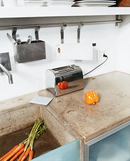 The cast-concrete sink, glass detailing, and steel appliances add to the clean, minimal, space-saving feel of the kitchen.