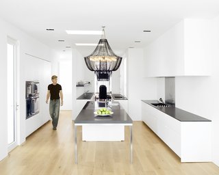 Hollis designed the kitchen--which features a Boffi kitchen system and Gaggenau appliances-- as three zones. The first centers around the stainless-steel-and-Zodiac-stone island, which is topped by a custom beaded chandelier by South African company TeamTwo Design. This zone functions as a place for food preparation, cooking, serving, and socializing. The second zone is the clean-up area, and the third is the bar.Photo by <br><br>Ben Mayorga Photography