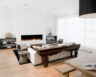 The living room and dining room were originally separated by a central fireplace, which Hollis removed to create this great room. She installed a custom eight-foot-long open gas fireplace in the living room (equipped with sensors that automatically turn it off when someone gets too near to the flames).Photo by <br><br>Ben Mayorga Photography