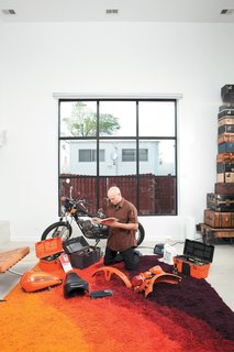 In the light-flooded living room, Hernandez does a little work on a 1976 Italian-made Harley-Davidson SXT125.