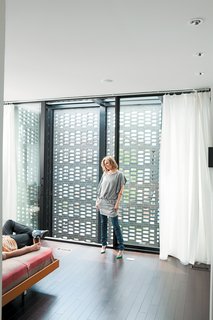 In the master bedroom, the couple enjoy the ample natural light that filters through the brick screen.