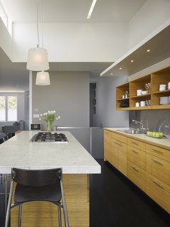 Raising the ceiling height in the kitchen meant that Willmer was also able to create a clerestory window (top left) that lets in western light in the evenings. Beyond the custom bamboo cabinets are stairs to the ground floor as well as half bathroom.<br><br>Photo by Ken Gutmaker