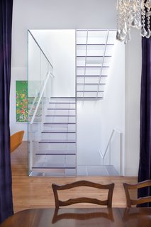 The view of the stairs from the dining room on the main floor highlights the stairwell's function as a lightwell. Samaha and Hart chose one-inch-thick Ecorsein by 3Form for the treads and risers, as it was the most transparent, scuff-resistent finish they could find. For the handrails, they used painted steel; for the center panel, a mix of acrylic and steel.<br><br>Photo by <br><br>Sharon Risedorph