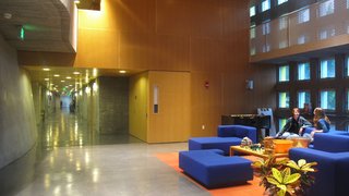 "I Live in a Steven Holl" - Photo 3 of 8 - Renee and Amanda chat in the Simmons mail room, which is also the lobby and used as a meeting place. You can see three levels of porosity -- perforated wood paneling, metal overhead railing, and windows in the concrete walls.