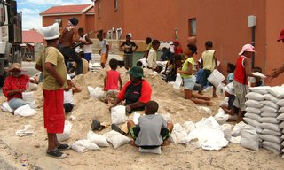 Mpahlwa took inspiration from the vernacular architecture of his youth in a rural part of the Eastern Cape, where people built homes from mud, water, and timber, to transform what is generally considered a nuisance—the abundance of sand—into an invaluable resource for holding down a house. Members of the community, seen here, gathered together to pack bags full of sand. Image courtesy Interactive Africa/ Design Indaba