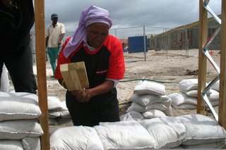 Once the frame of the house was constructed, the townspeople filled the wall space with sandbags. Here, Olga Jonkers uses a handmade tool to compact the bags that will become the walls of her future home. Image courtesy Interactive Africa/ Design Indaba