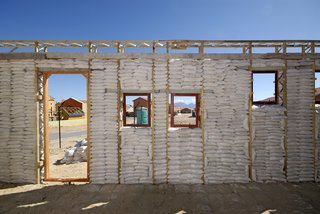 After the walls of the first-floor frames were filled tightly with sandbags, the workers plastered wire mesh onto the exterior. Image courtesy Interactive Africa/ Design Indaba