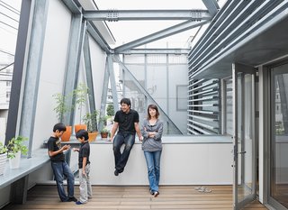 Small Box Home with Black Metal Facade in Japan - Photo 4 of 14 - Slotted between the street-side enclosure and the living area is a breezy second-floor terrace. Brise soleil slats shade the interior. Yatabe’s steel fabrication company created the robust, trusslike armature that extends from the house to support the deck and facade.