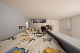 Even the most petite Parisians are chic. For this 10th arrondissement kids' room renovation, a multitude of shelves and storage let Eva hide her stuffed animals, books, and secret notebooks—with a small corner looking out of the window onto the Paris landscape outside and the window to her brother inside. Photo by Stéphane Chalmeau.