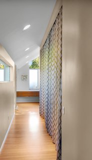 Bedroom Addition in Seattle - Photo 10 of 16 - The master suite is connected to the original house by a long hallway, pictured here, which hides a closet behind the colorful curtains.