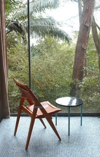 Her folding side chair, against the floor-to-ceiling window wall of the Glass House. Photo courtesy Espasso.