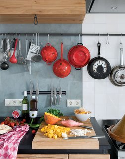Black stone worktops, waxed concrete walls, and the traditional rustic tiles (called "witjes") give textural and tonal variety and offset the warm woody tones that dominate this kitchen. The rustic theme is continued in the iron hooks and bars—simple but effective fittings.