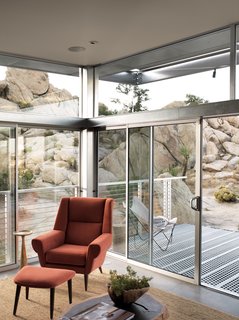 Small "Hybrid Prefab" Home in the Desert - Photo 6 of 10 - The main living area extends to the deck through sliding glass doors. The orange David Chair and ottoman were designed by Palm Springs-based interior designer Christopher Kennedy and are from his eponymous line of furniture. Kennedy did the interior design for the whole house, playing a large role in choosing the decor and eco-friendly surfaces.