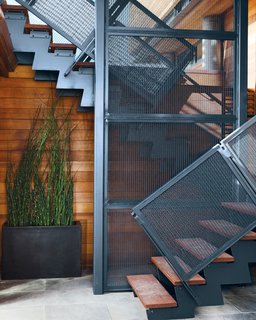 The steel stairwell that connects the garden-level patio with the new living space performs double duty as an anchor attached to the foundation.