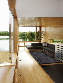The living area overlooking the lake includes a banquette that seats eight and sleeps three, upholstered with a fully compostable Climatex Lifecycle fabric. A low-slung horizontal side window allows a sliver of light in yet retains privacy.