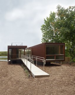 The entrance ramp leads to the smaller module, containing a bedroom, a bathroom and a rooftop observation deck; the module at right includes a bedroom, bathroom, the kitchen and the living area.