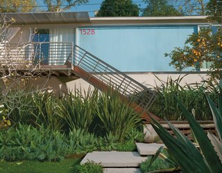 Good Idea Studio redesigned the front facade with a welded tube steel staircase, an aluminum-and-polycarbonate awning, and fiber cement-board paneling painted "Pool Party" blue.